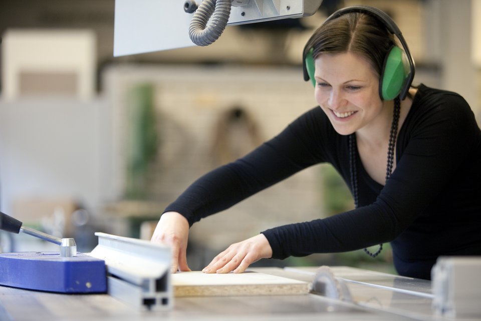 Eine Studentin arbeitet mit Holz in der Modellbauwerkstatt