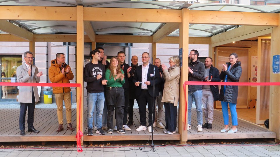 Gruppe Personen auf Terrasse von Block 4 hinter zerschnittenem roten Band
