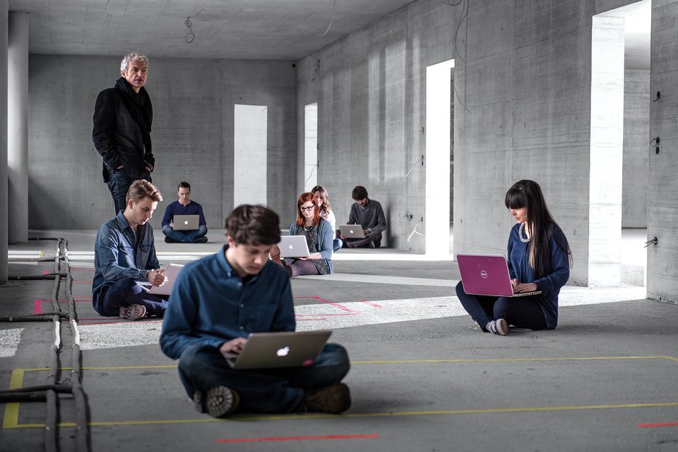 Studierende arbeiten auf dem Boden sitzend am Laptop 