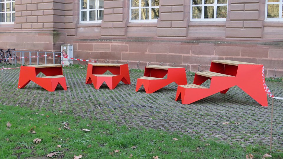 Vier rote Sitzmöbel der Produktlinie STOOP rechts vor Hauptgebäude der Hochschule