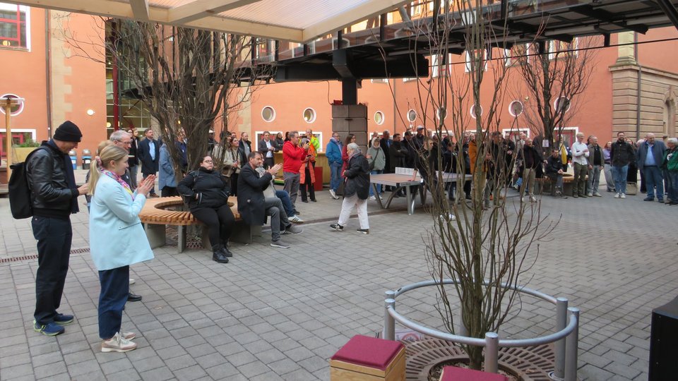Blick aus Mehrzweckraum in Innenhof mit Gruppe Personen