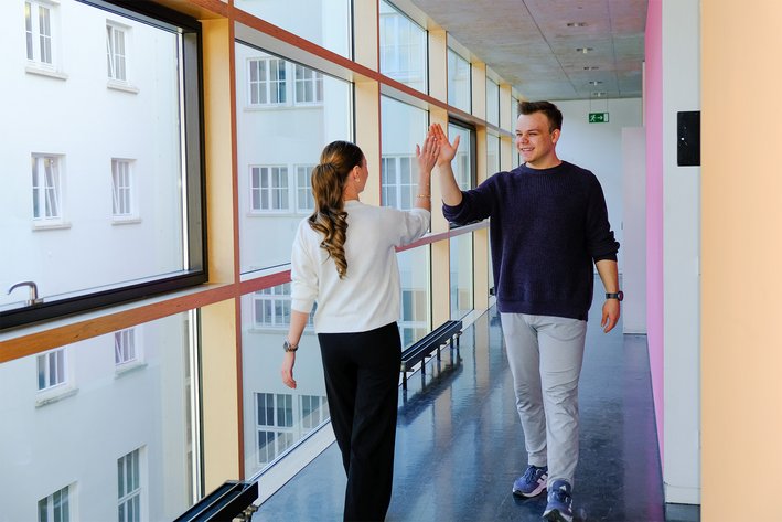 A male and female student giving each other a ‘high five’