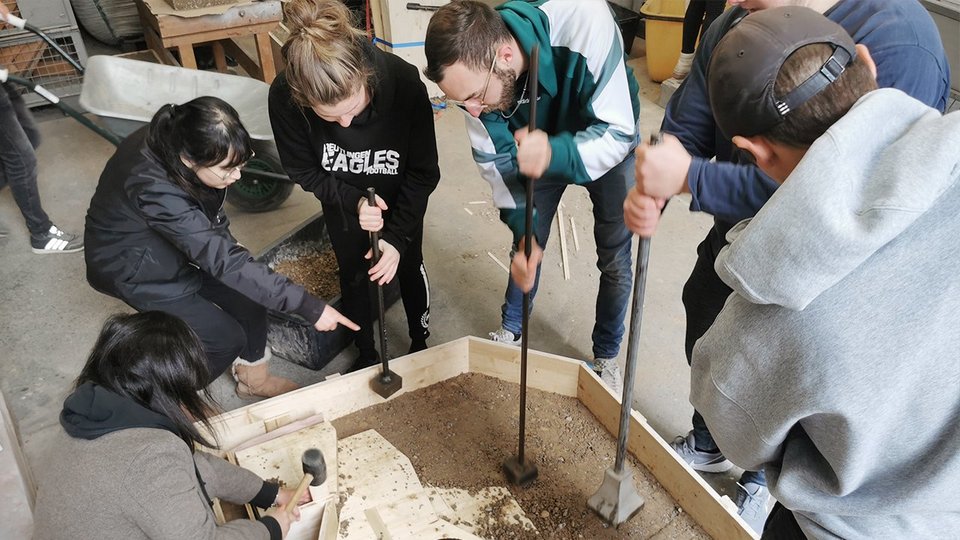 Studierende bei der Bearbeitung eines Stampflehmmodells