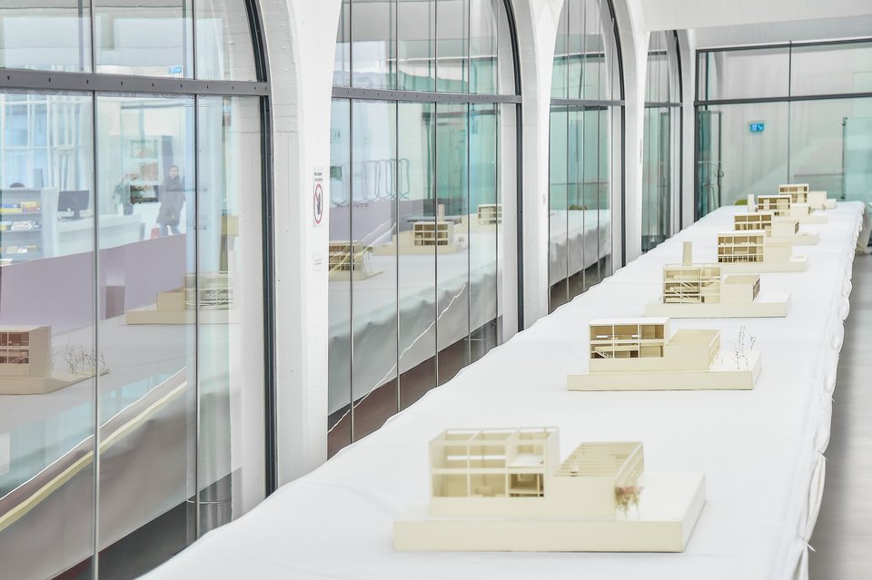 Mehrere Architekturmodelle auf einem langen Tisch bei der Ausstellung