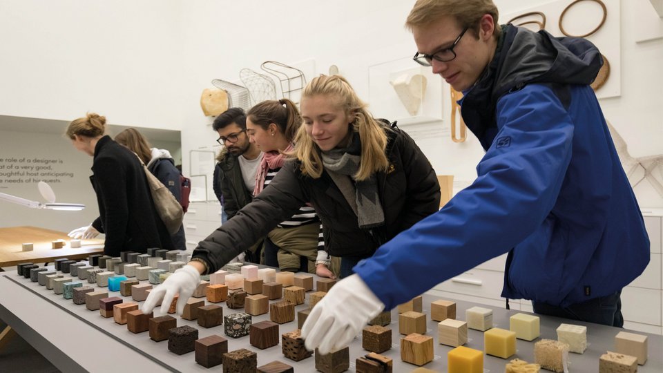 Ausstellung im Vitra Design Museum: Hände greifen verschiedene Materialien in Würfelform