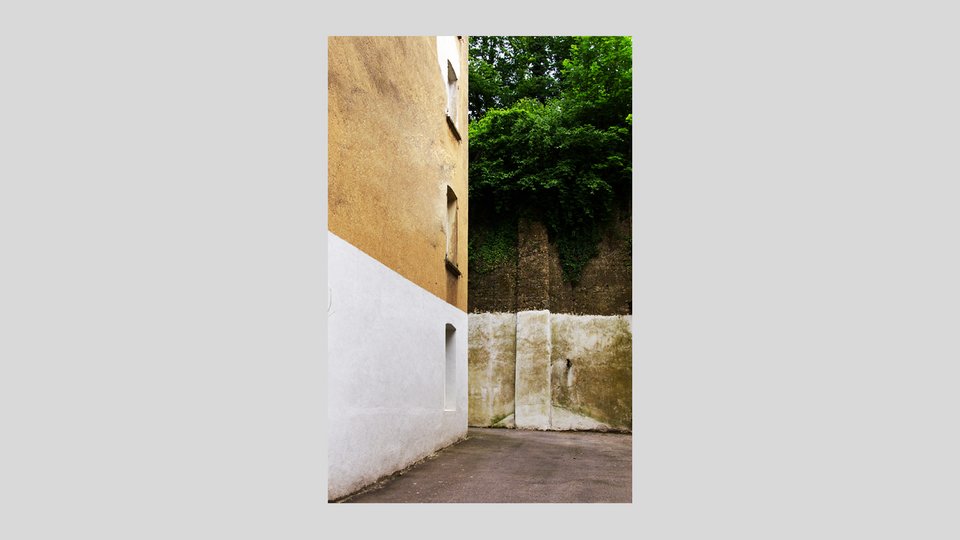 Architekturfotografie einer Fassade, im Hintergrund Mauer und Bäume