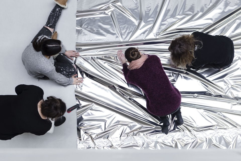Vier Studierende sitzen auf dem Boden und bearbeiten eine silberne Folie