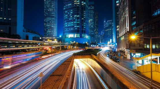 Eine Straße mit dichtem Verkehr und Hochhäuser bei Nacht