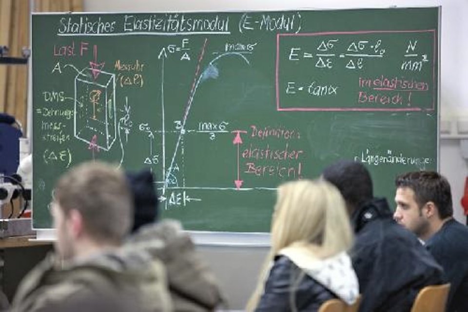 Studierende sitzen vor einer beschriebenen Tafel