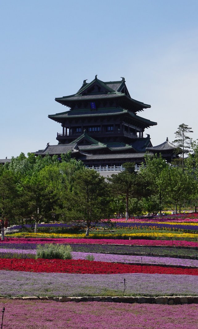 Eine Parkanlage mit Blumen und ein Gebäude im asiatischen Baustil