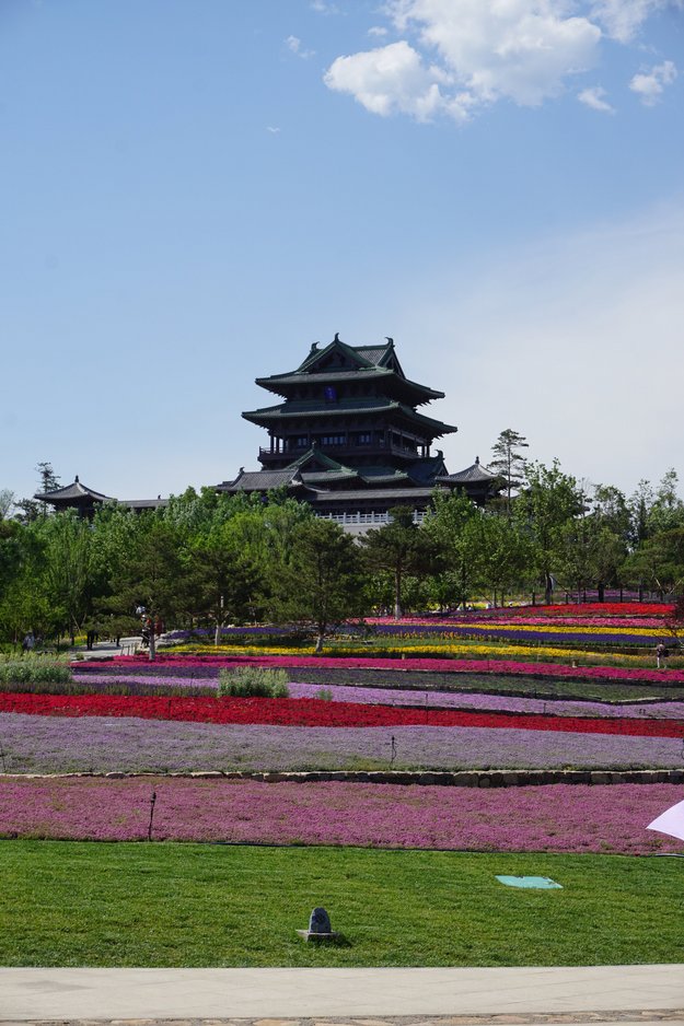 Eine Parkanlage mit Blumen und ein Gebäude im asiatischen Baustil