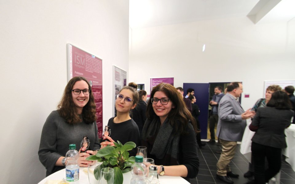 Drei ISM-Absolventinnen stehen an einem Tisch zusammen