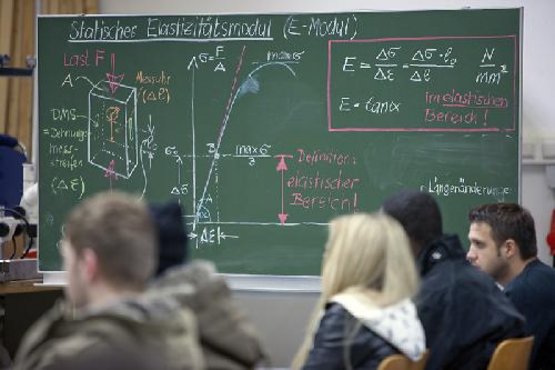 Studierende sitzen vor einer beschriebenen Tafel