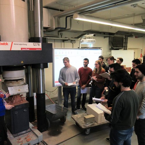 Eine Gruppe von Studierenden vor einem Gerät für Materialprüfung