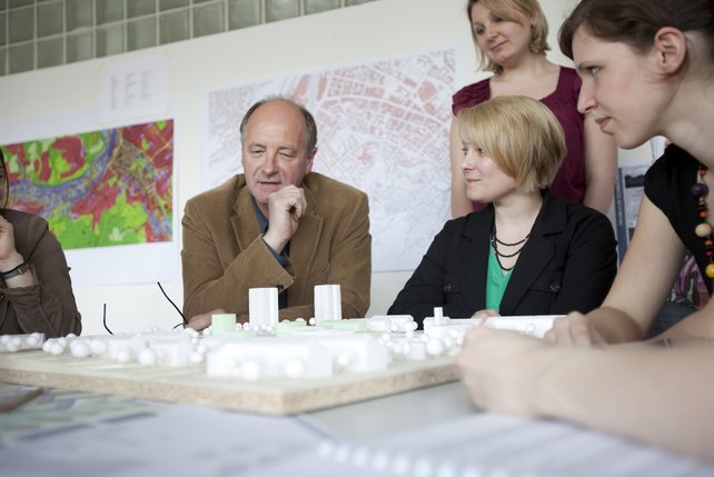 Studierende und ein Professor besprechen ein städtebauliches Modell