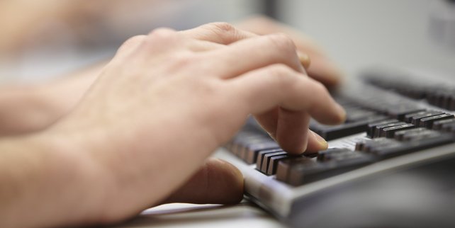 Eine Hand schreibt auf einer Tastatur