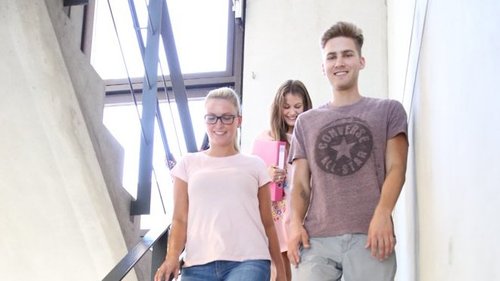 Drei Studenten laufen eine Treppe herunter