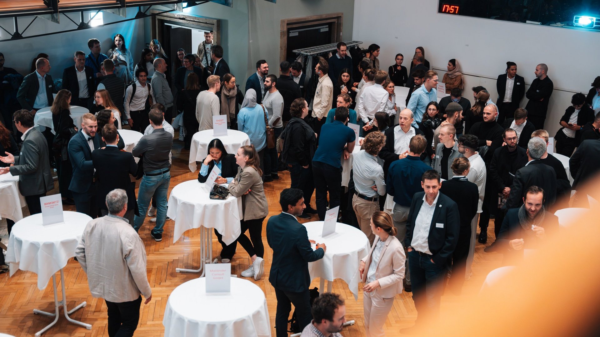 Blick in die Aula auf feierlich gedeckte Stehtische und viele Menschen