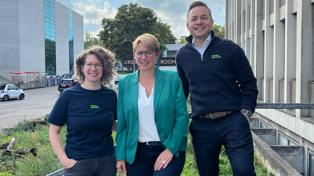 Drei Personen stehen vor einem Gebäude