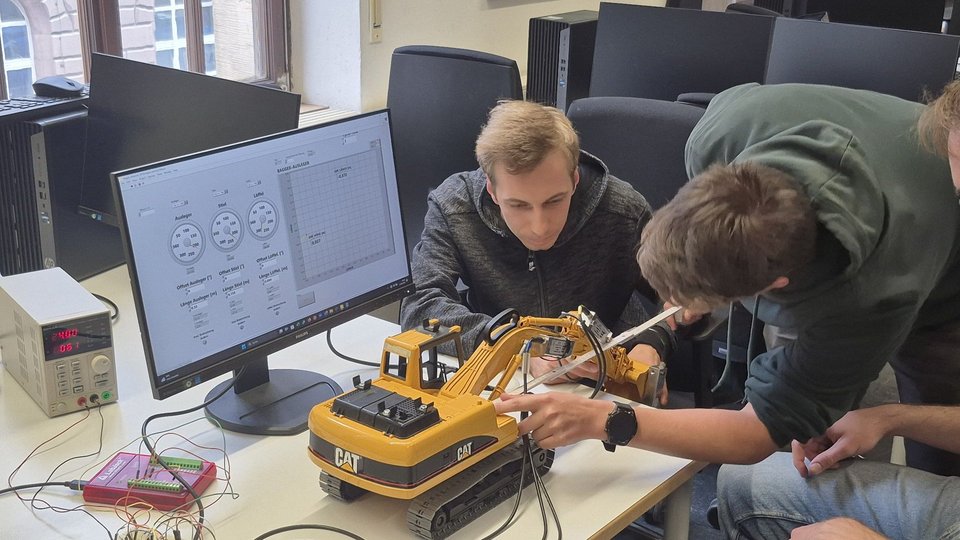 Studenten konfigurieren Mess-Sensoren an einem Bagger-Modell