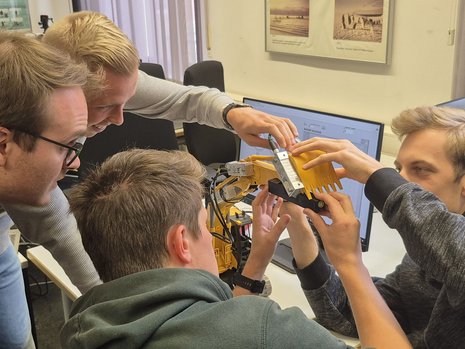 Studenten konfigurieren Mess-Sensoren an einem Bagger-Modell